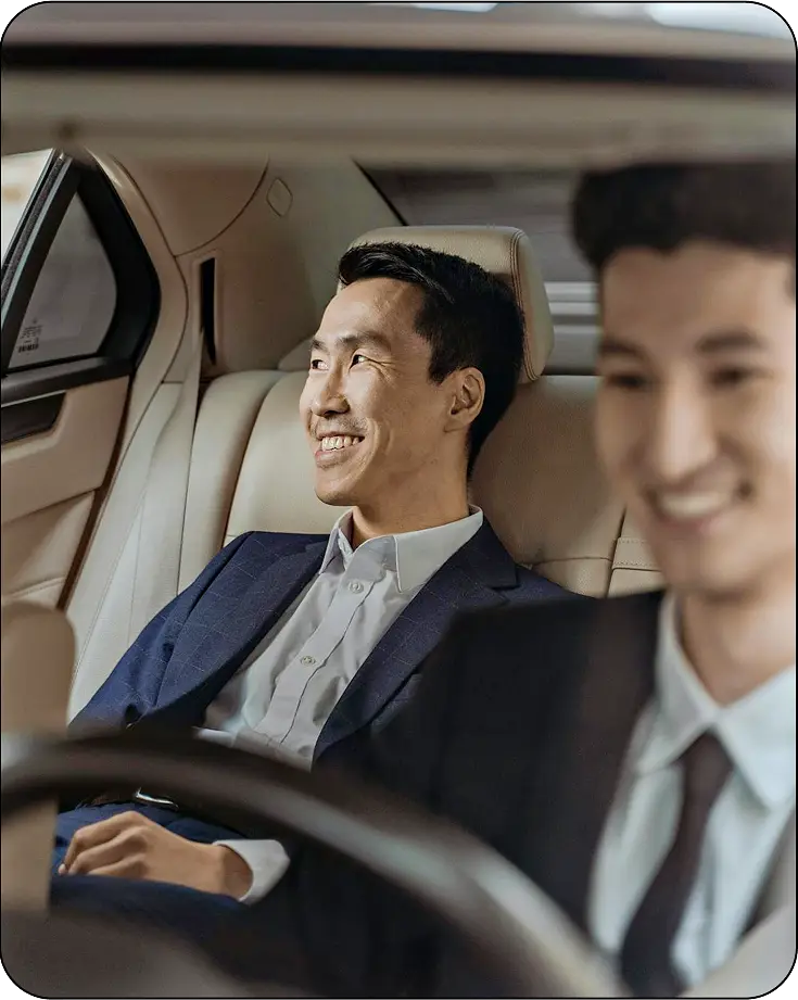 image of someone sitting inside a car—smilling while he being drived